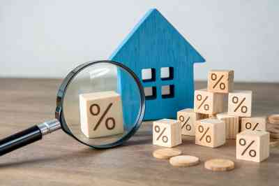 Lupe, Holzhaus und Würfel mit Prozentzeichen